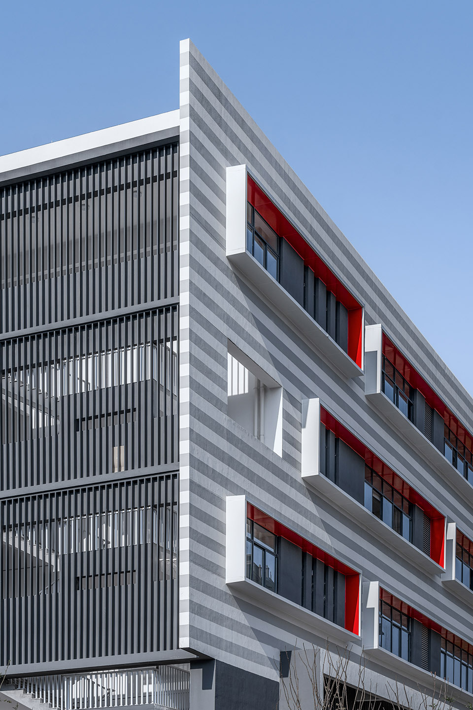 ▼灰白条纹真石漆和红色的窗框的组合▼从街道看向建筑▼建筑立面沿着